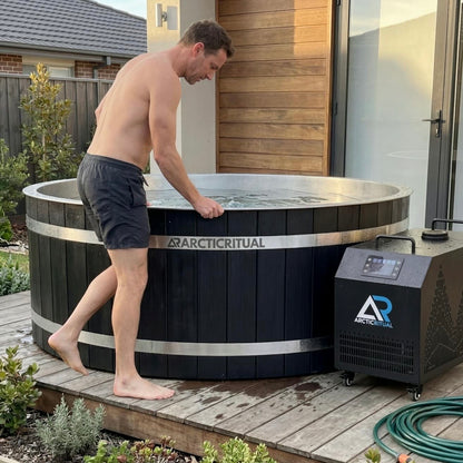 Person stepping into Arctic Ritual Cedar Pro cold plunge tub with external chiller system installed outdoors