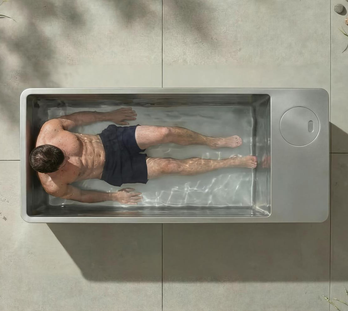Top-down view of man in outdoor cold plunge tub with clear water, demonstrating ice bath recovery and cold exposure in a modern backyard setting