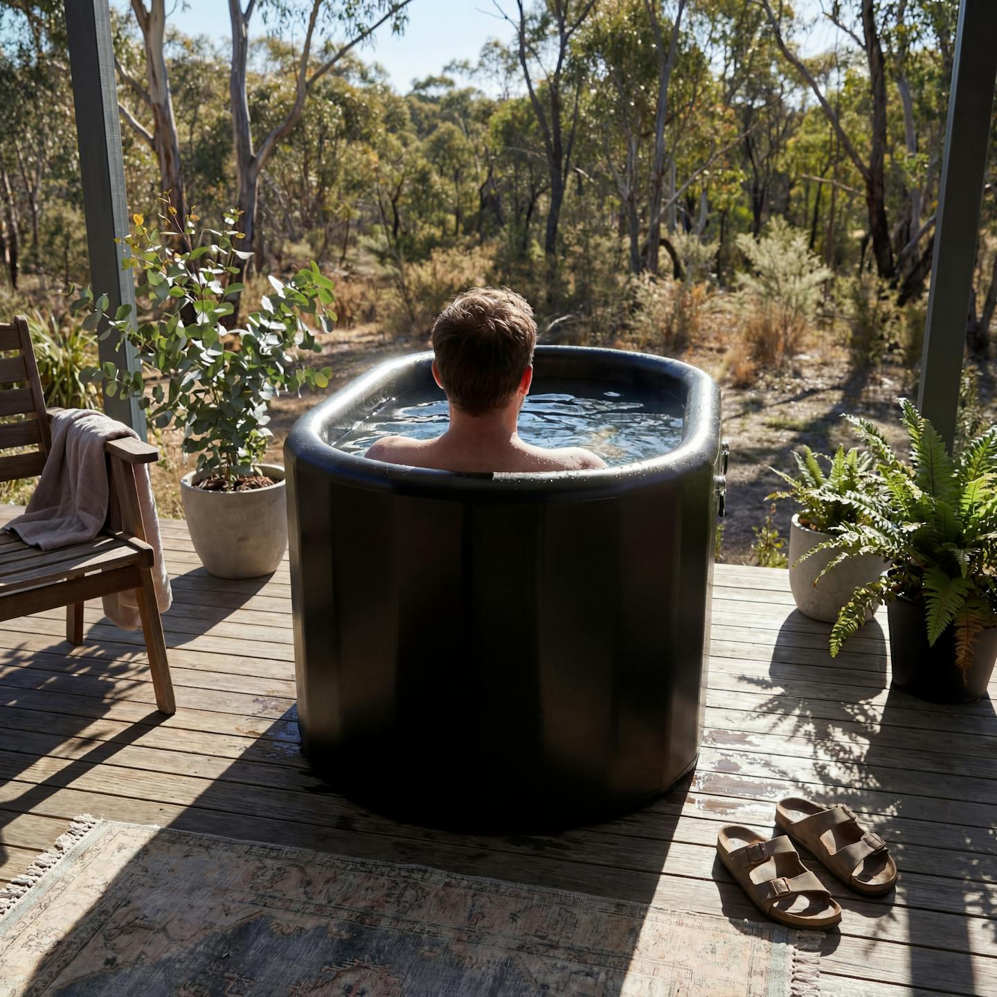 Person relaxing in Arctic Ritual Lite+ Barrel cold plunge tub on outdoor deck surrounded by nature