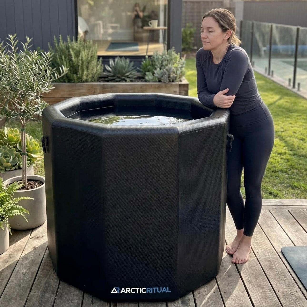 Person standing beside Arctic Ritual Lite+ Barrel cold plunge tub outdoors showing full size and depth