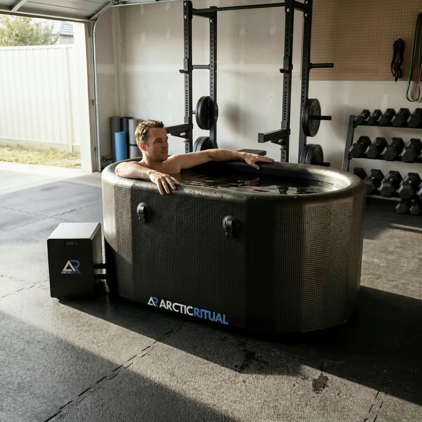 Person relaxing in Arctic Ritual Lite+ cold plunge tub with chiller inside home gym for post workout recovery
